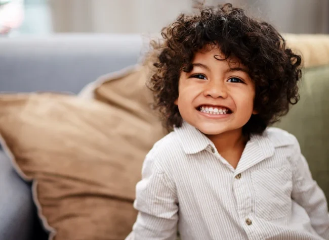 smiling-child-poses-indoors-wearing-striped-button-2026-03-25-03-59-03-utc