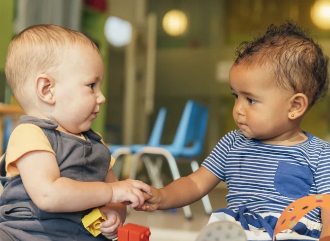 two-toddlers-interact-with-toys-in-a-playroom-2026-03-09-23-50-35-utc